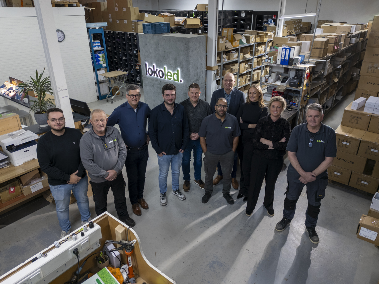 Team van LokoLed in magazijn tussen rekken met dozen en werktafels